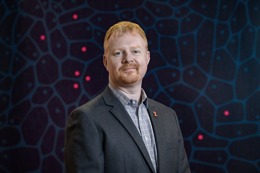 Andrew Leakey standing in front of a designed background